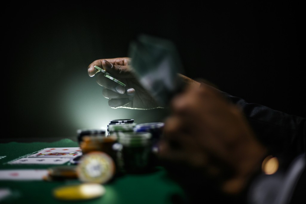 Low-light photograph of poker chips and playing cards on a green felt table